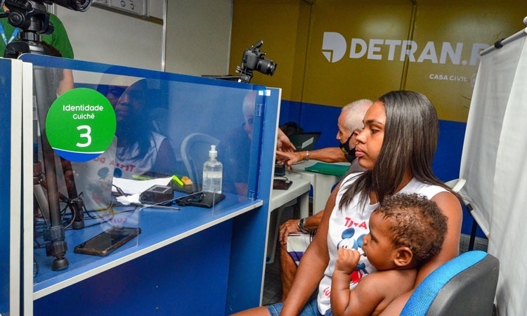 Mãe e filhos emitindo a carteira de identidade em um dos postos