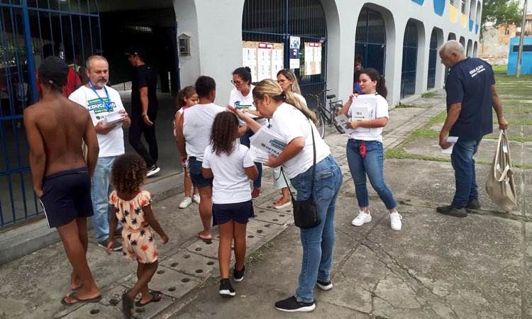 Funcionários do Detran distribuem cartilhas e quebra-cabeças para crianças em frente ao CIEP, em Bangu