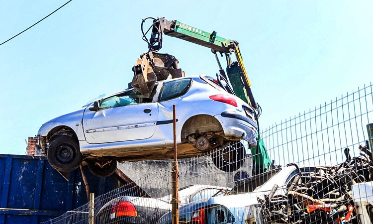 carro suspenso por guindaste em ferro-velho