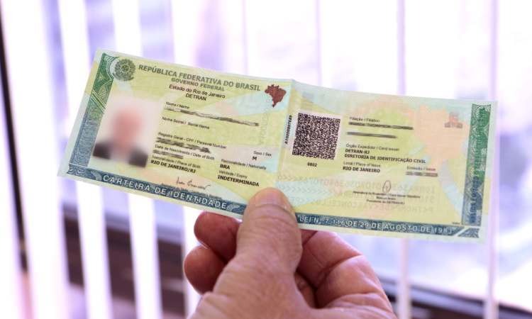 mão de um homem segurando uma Carteira de Identidade Nacional