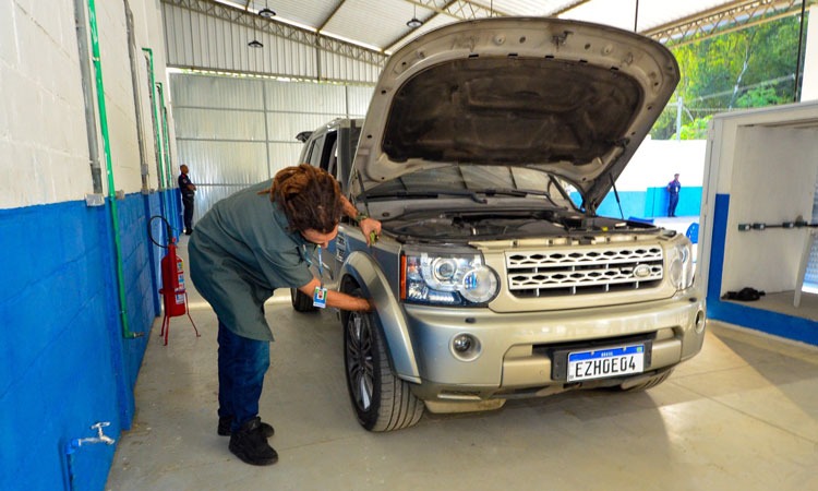 Funcionário do Detran faz vistoria em veículo com capô aberto