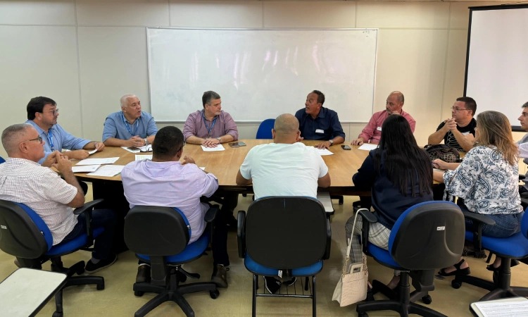 Doze pessoas reunidas entorno de uma mesa, dentre elas o vice-presidente do Detran e o diretor de habilitação