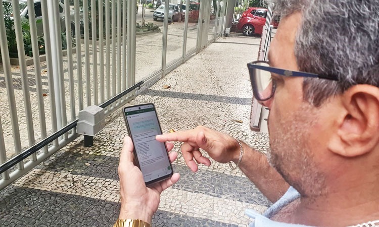 Homem em calçada acessa o serviço de atendimento por whatsapp em seu celular