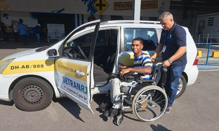 Cadeirante posa em frente a carro adaptado do Detran dentro de área de prática de exame de direção