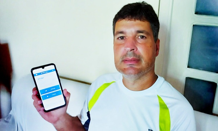 homem mostra celular com a tela do Posto Digital