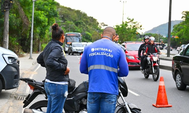 agente de fiscalização do Detran aborda motociclista em via pública, em operação do Governo do |Estado