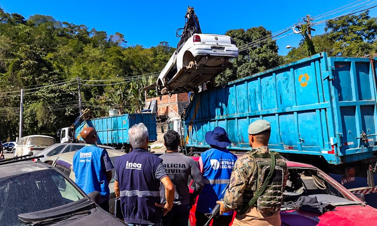 Agentes do Detran observam operação com guindaste em ferro-velho