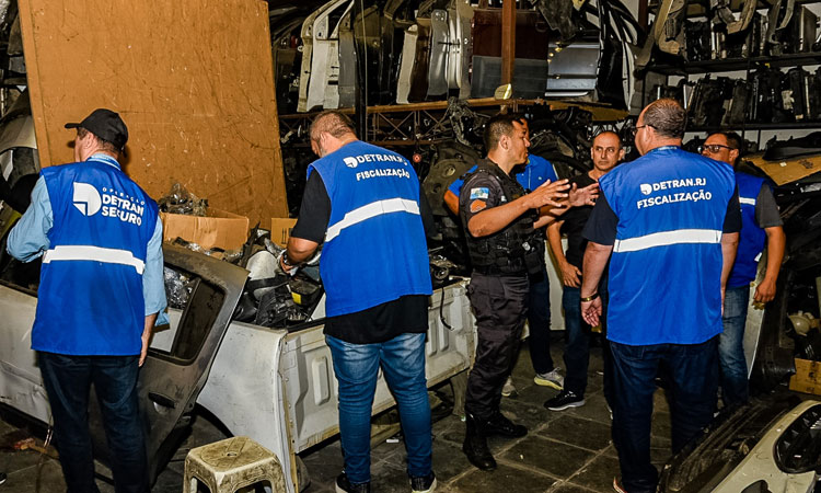 Agentes do Detran em conjunto com Polícia Civil averiguam peças de carro em ferro-velho clandestino, em Bangu
