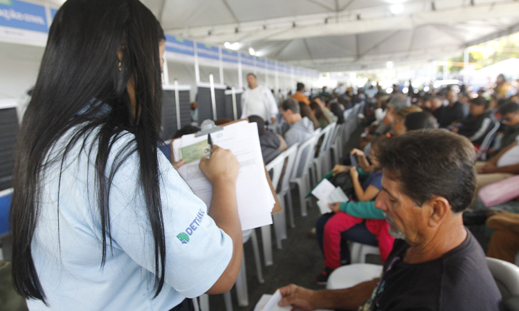 Uma atendente do Detran coleta informações de usuário interessado em obter a Carteira de Identidade Nacional